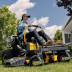 Person operating a Cub Cadet Ultima Z3 54 Zero Trun ride on lawn mower in a grassy area with trees and a house in the background. Mower City Albury