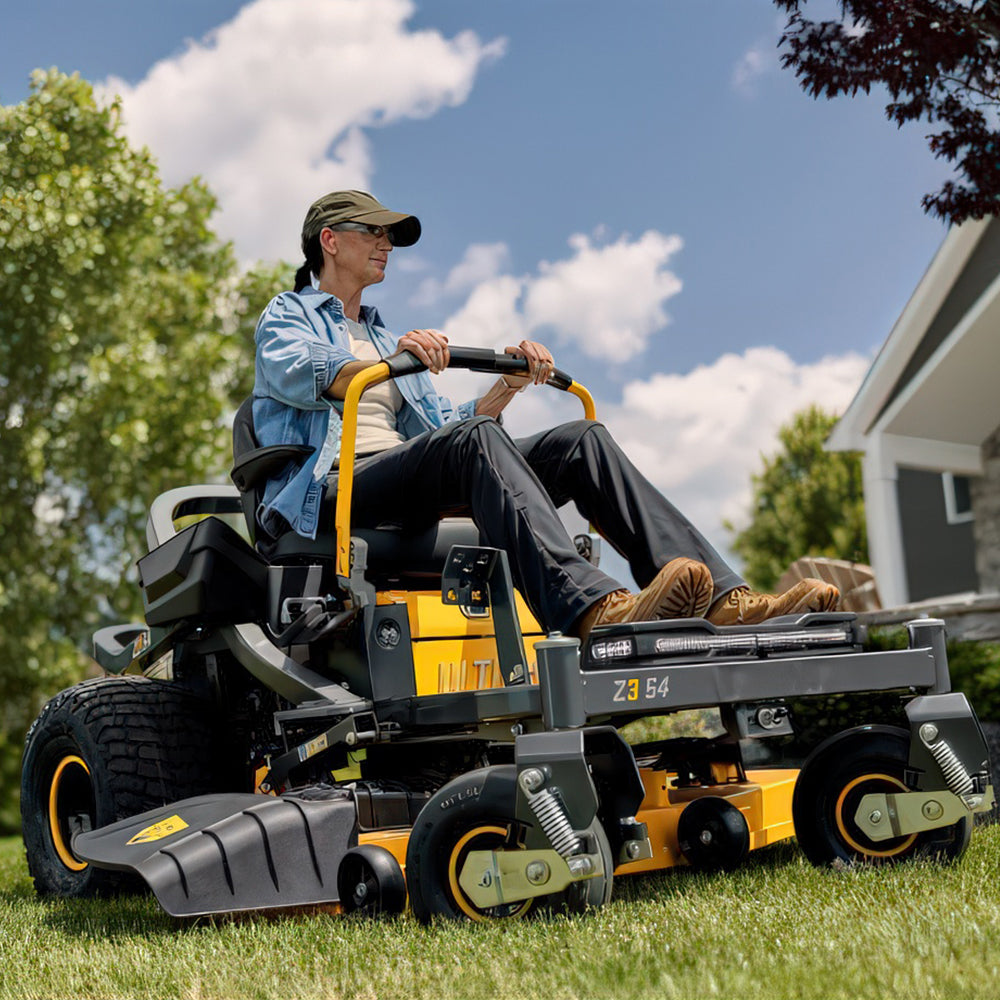 Person operating a Cub Cadet Ultima Z3 54 Zero Trun ride on lawn mower in a grassy area with trees and a house in the background. Mower City Albury