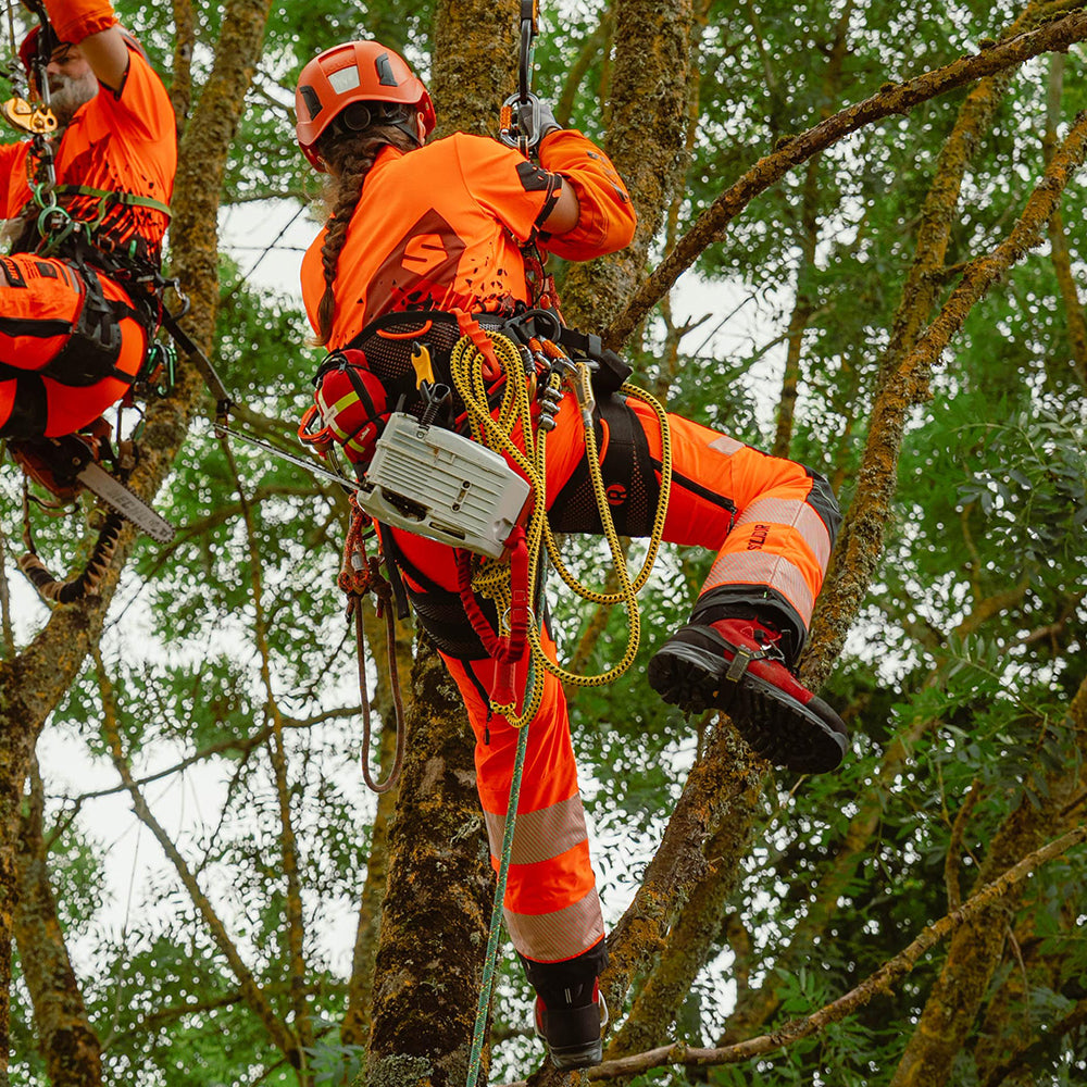 woman arborist wearing Solidur Premium hi-vis orange Class 1 Design A chainsaw trousers. 6-layer protection, 1.35 kg, slim fit, SRT-ready. Available at Mower City Albury.