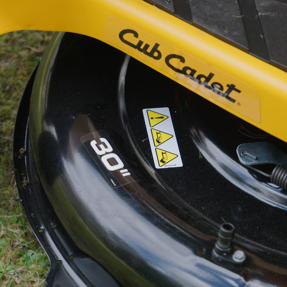 Close-up of a black and yellow Cub Cadet lawn mower deck, showing the 'Cub Cadet' logo, a '30"' size sticker, and safety warning labels. CC30 HX Mini Rider. Talk to the Team at Mower City Albury