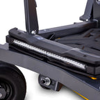 Cub Cadet Ultima Z2 46 zero-turn mower. Close-up of a black metal utility cart or trailer frame with a long rectangular LED light bar mounted across the side, a black wheel, and a small yellow accent strip for larger lawns and blocks up to four acres. Available at Mower City Albury.