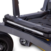 Cub Cadet Ultima Z2 46 zero-turn mower. Close-up of a black metal utility cart or trailer frame with a long rectangular LED light bar mounted across the side, a black wheel, and a small yellow accent strip for larger lawns and blocks up to four acres. Available at Mower City Albury.